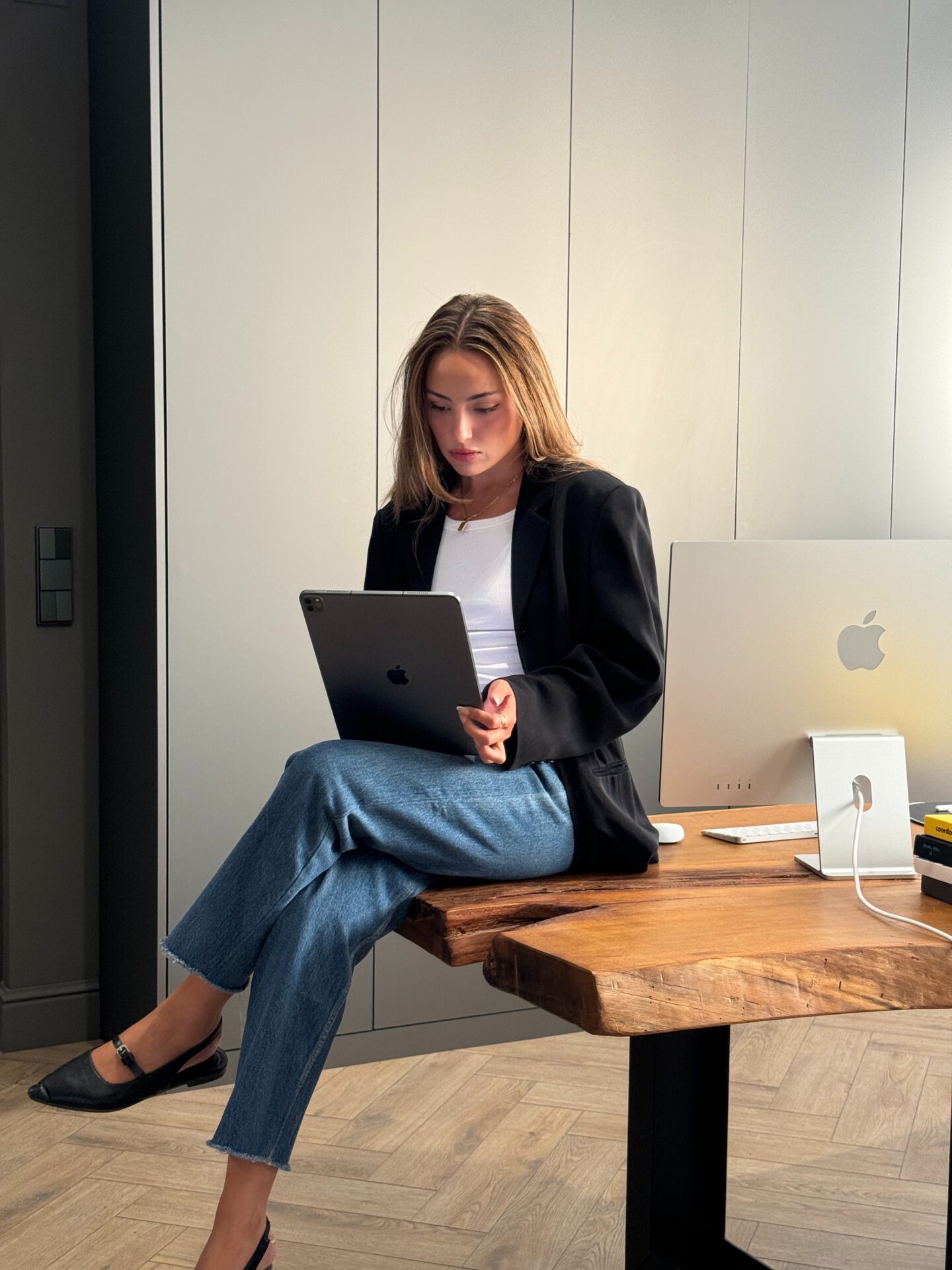 A creative professional reviewing social media strategies on an iPad, seated in a sleek, modern workspace that reflects premium branding and innovative solutions for luxury businesses.